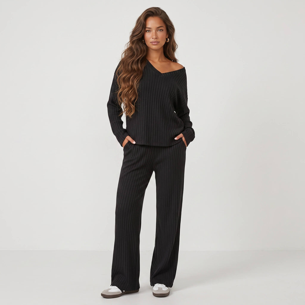 Model wearing black 2-piece ribbed knit pajama set with long-sleeve V-neck pullover and matching lounge pants